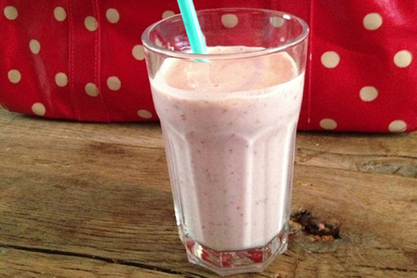 Aardbeiensmoothie in een glas met een blauw rietje
